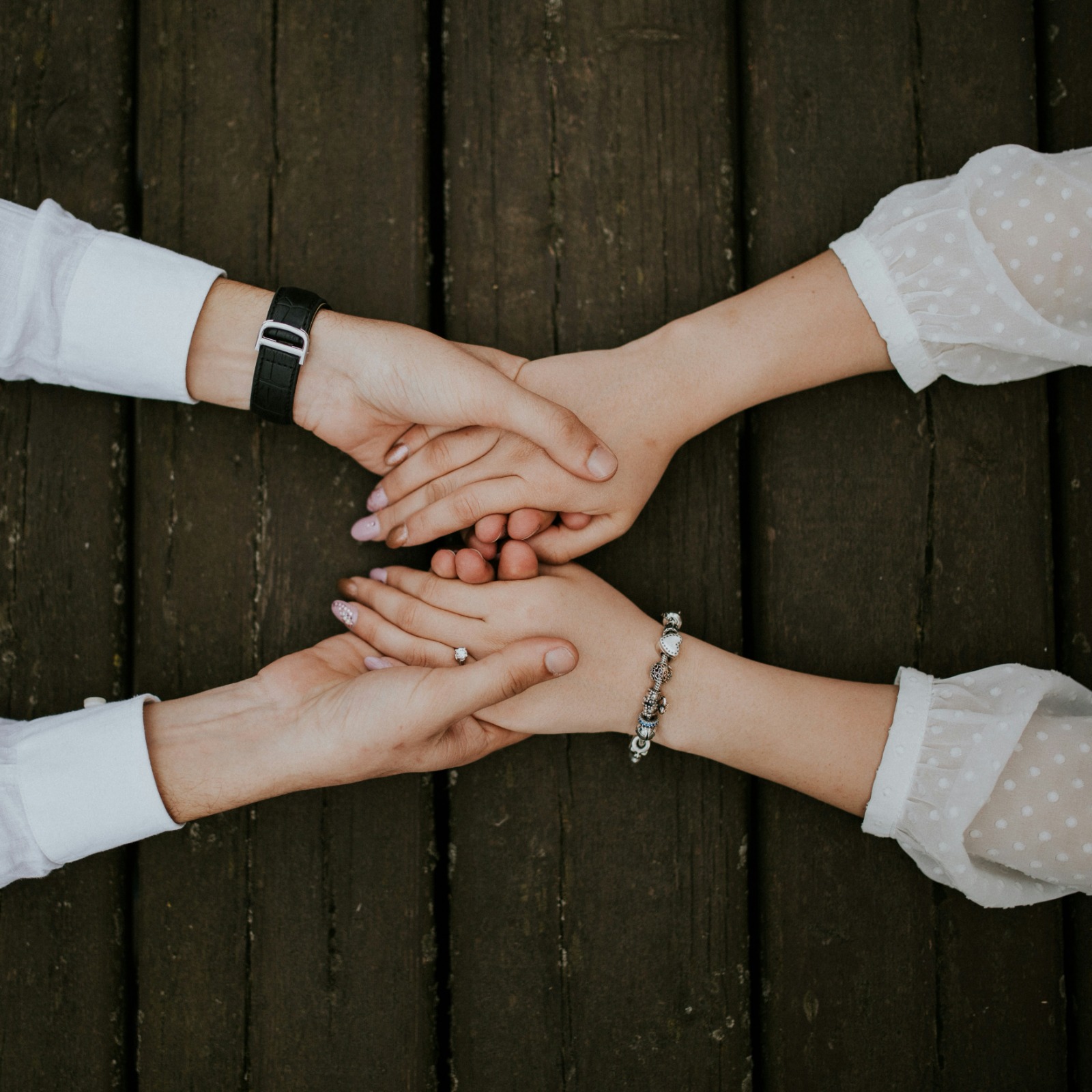 Four people joining their hands together in a gesture of mutual support